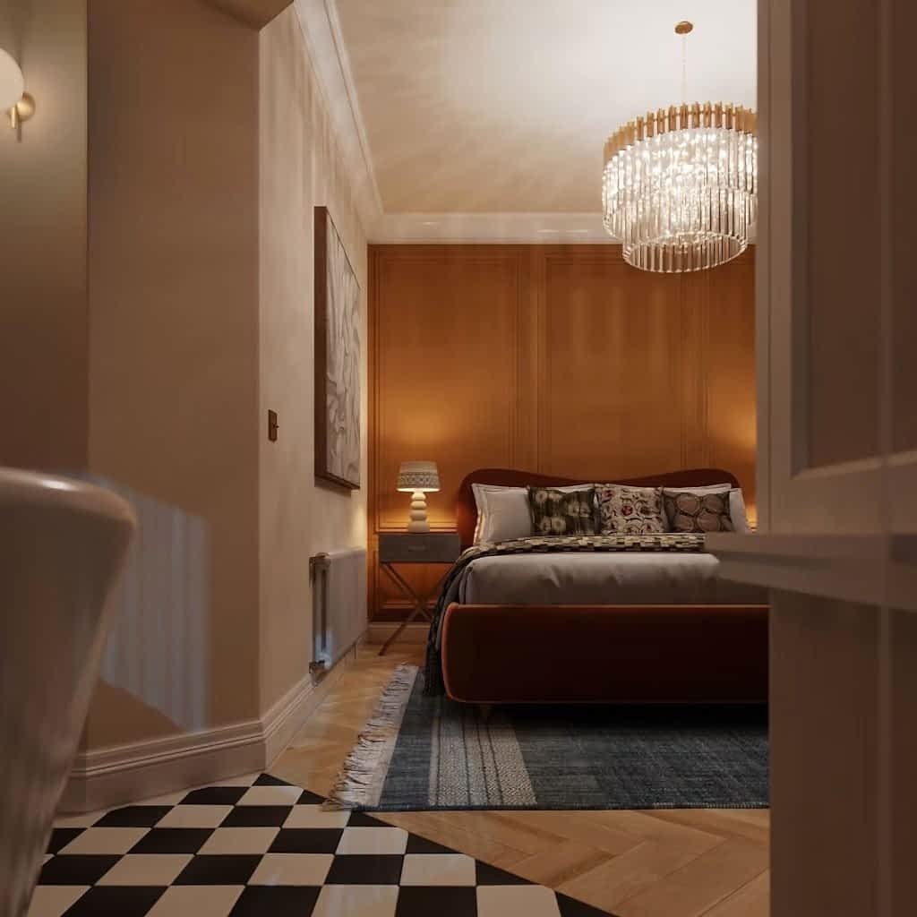 Bedroom with a rust velvet bed, a burnt-orange panelled wall, a glass chandelier and a checkerboard tiled floor.