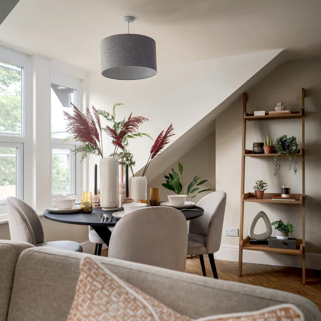 A beautifully staged dining nook in a Grove Road, Harrogate property by WildKind Interiors. This setup features a matte black round table set for four with neutral dinnerware, amber-hued...