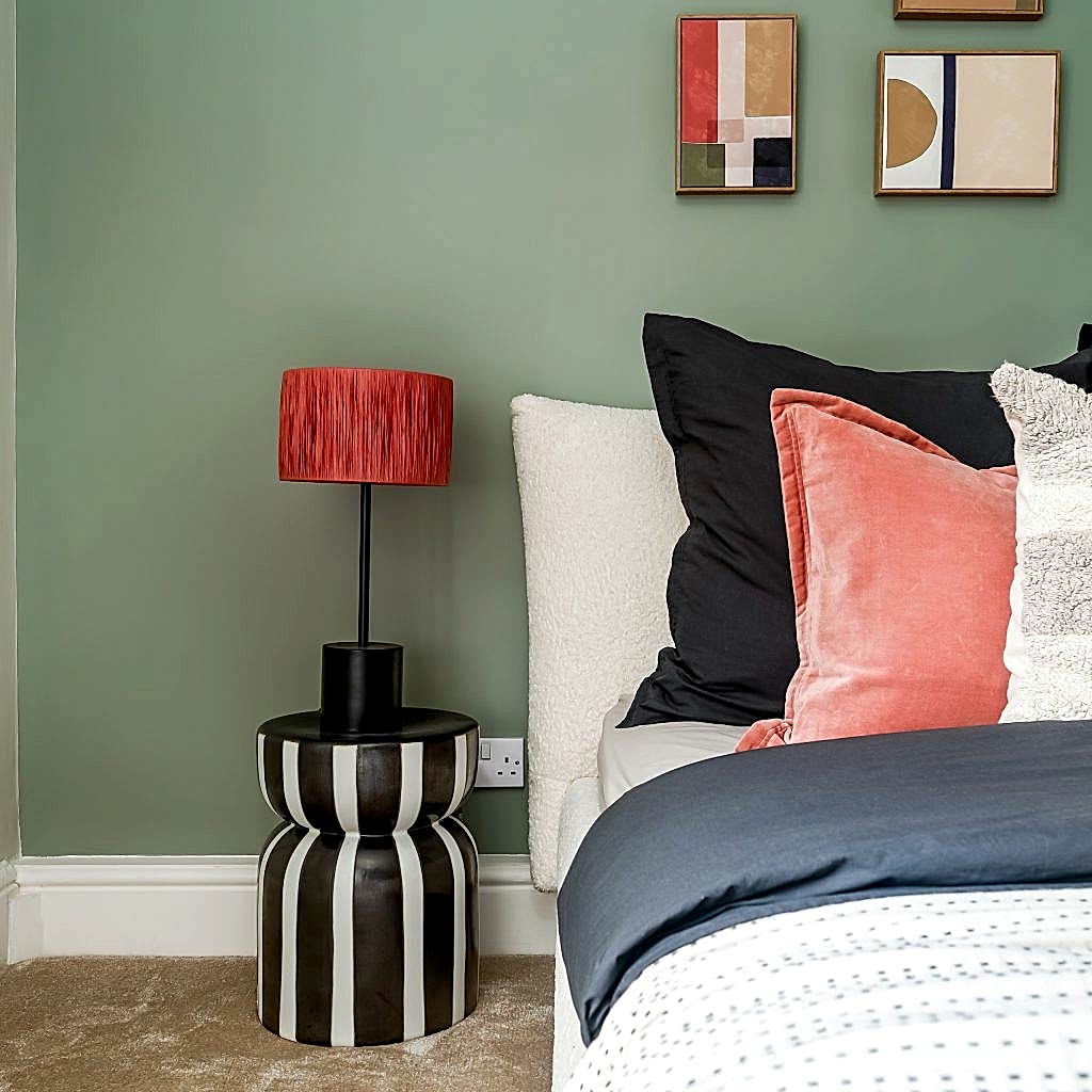 A striking bedroom accent vignette staged by WildKind Interiors for a Grove Road, Harrogate property. Featuring a sage-green accent wall behind a plush bed layered with black, coral velvet...