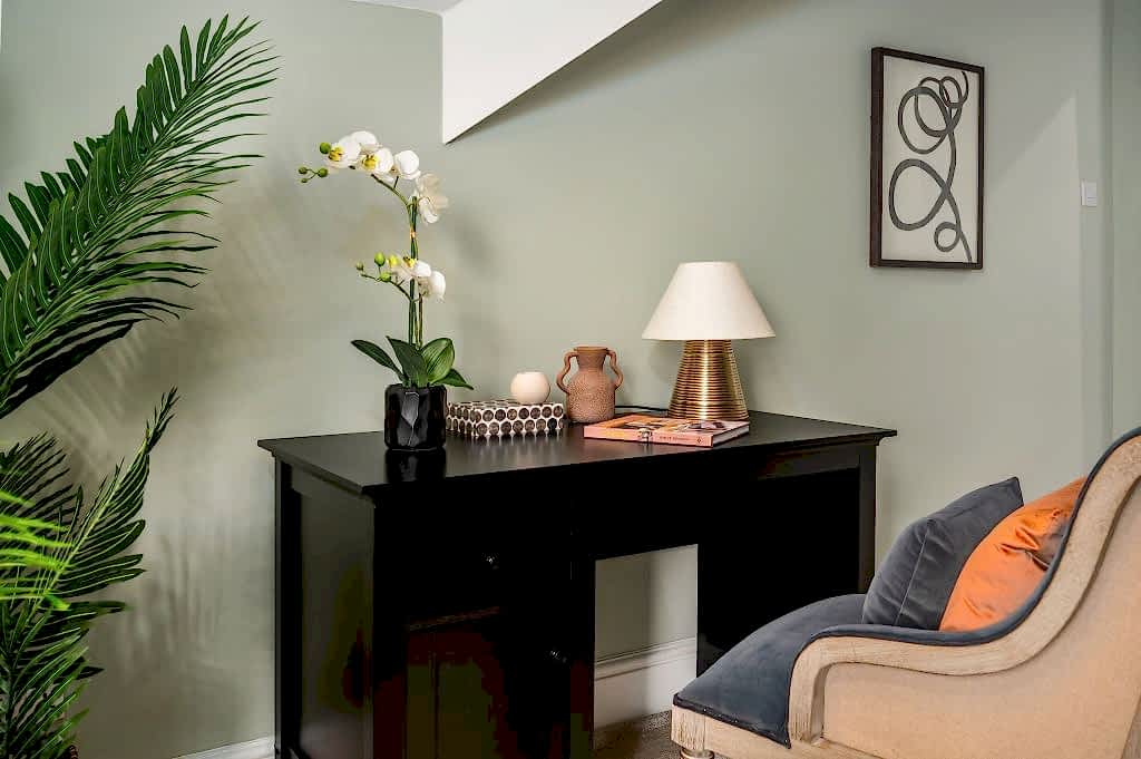 Study nook with a black writing desk, table lamp and an adjacent armchair.