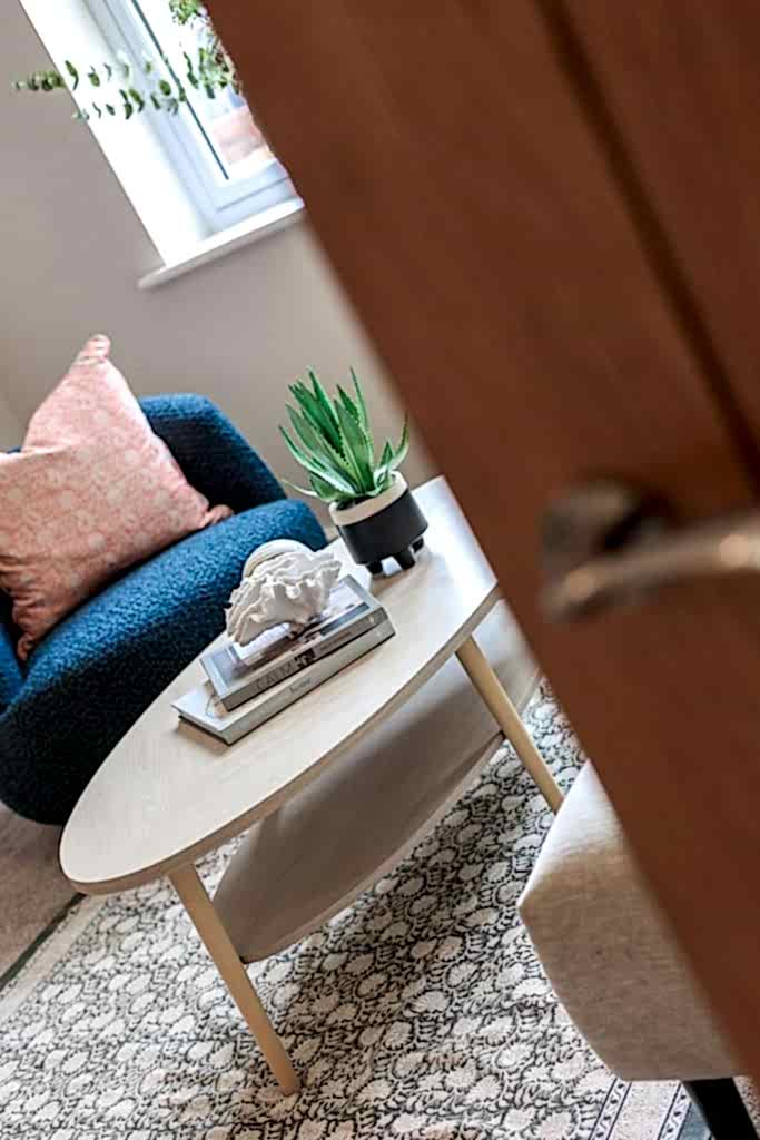 A cosy seating nook in a Huntingdon, York home staged by WildKind Interiors. The vignette features a light wood oval coffee table with a decorative coral sculpture, coffee-table books...