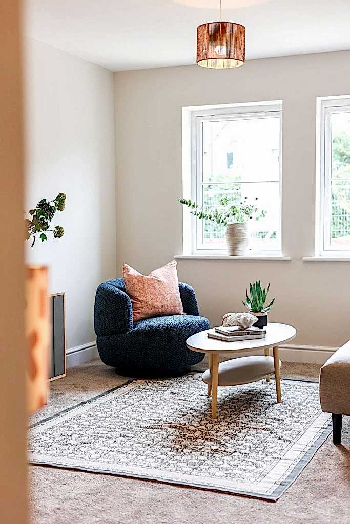 A warm seating corner in a Huntingdon, York home professionally staged by WildKind Interiors. The vignette features a textured navy armchair accented with a blush pink cushion, a light wood...