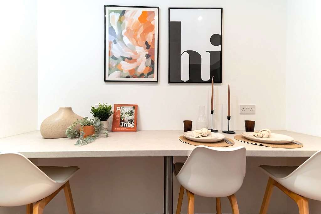 Communal dining space with a breakfast counter, sculptural vases and bold graphic prints.
