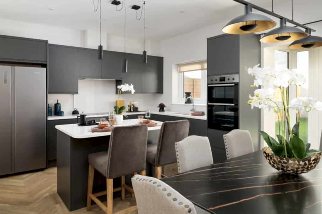 A contemporary open-plan kitchen and dining area professionally staged by WildKind Interiors. This project features sleek dark cabinetry, a white island with barstool seating, modern...