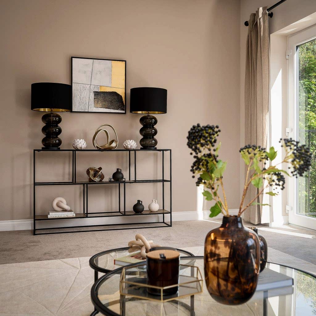 A chic living room vignette expertly staged by WildKind Interiors, featuring a slim black console table with sculptural decor and statement black-and-gold lamps, abstract wall art above...