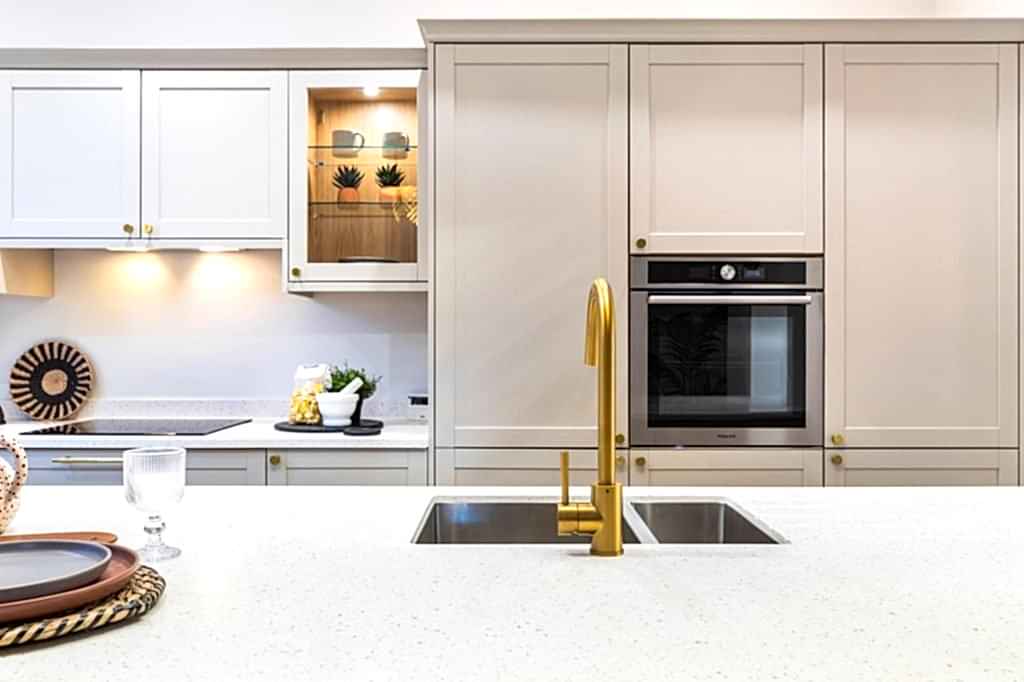 This beautifully staged Scartho kitchen features a central island topped with a crisp, speckled quartz countertop, accentuated by a sleek gold-finish mixer tap and a stainless-steel double...