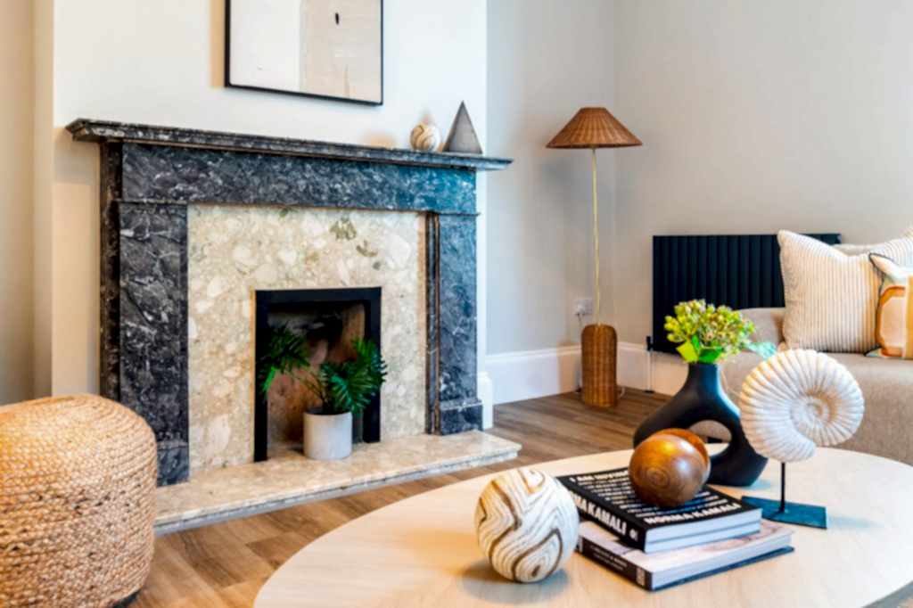 This elegantly staged living area in Scartho, Lincolnshire features a luxurious black-and-white marble fireplace with a contrasting pale stone hearth. A woven jute pouffe sits beside...