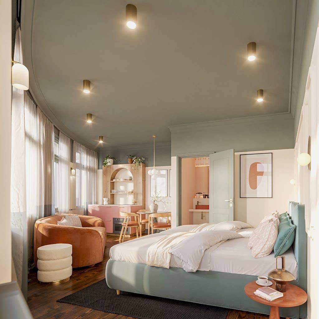 Studio suite pairing a bed with a coral-toned lounge area, statement pendant lighting and framed art.