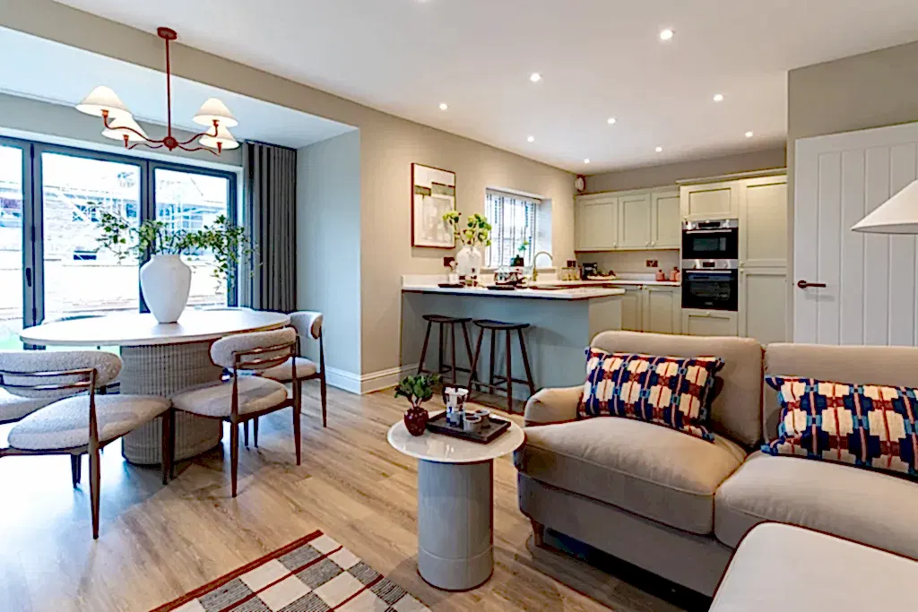 Open plan kitchen, dining and living space with a sculptural pendant, round dining table and patterned cushions.