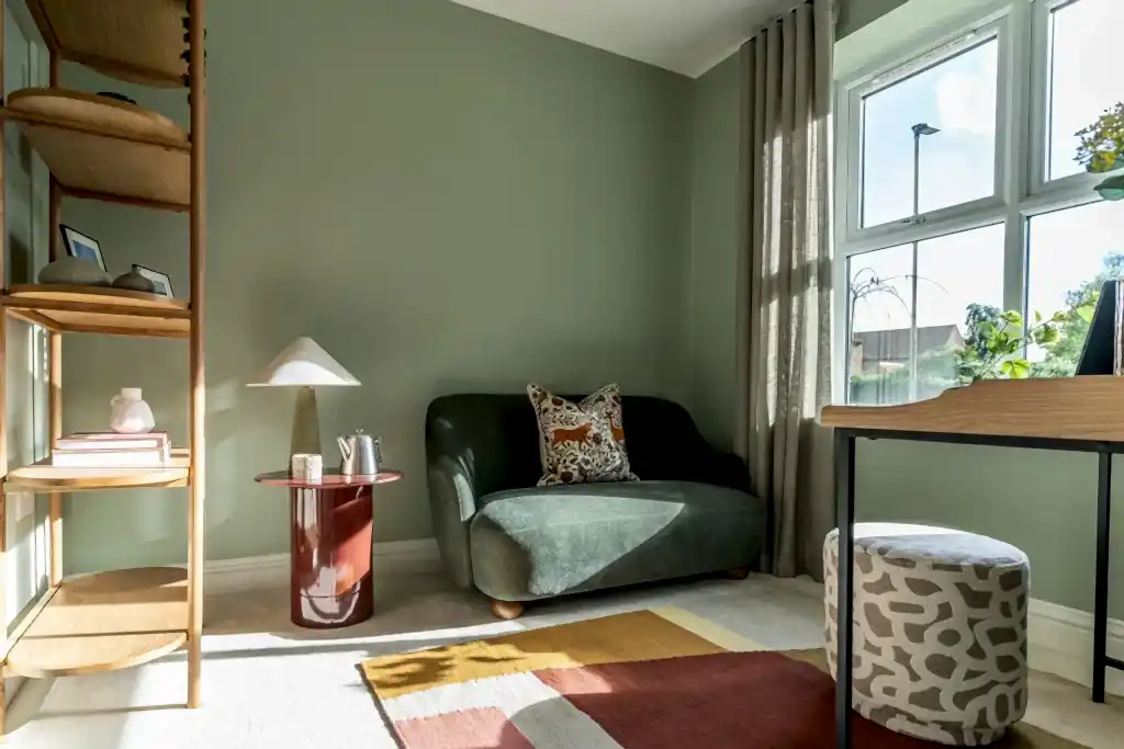 Snug with a green velvet sofa, oak shelving and a bold patterned rug.