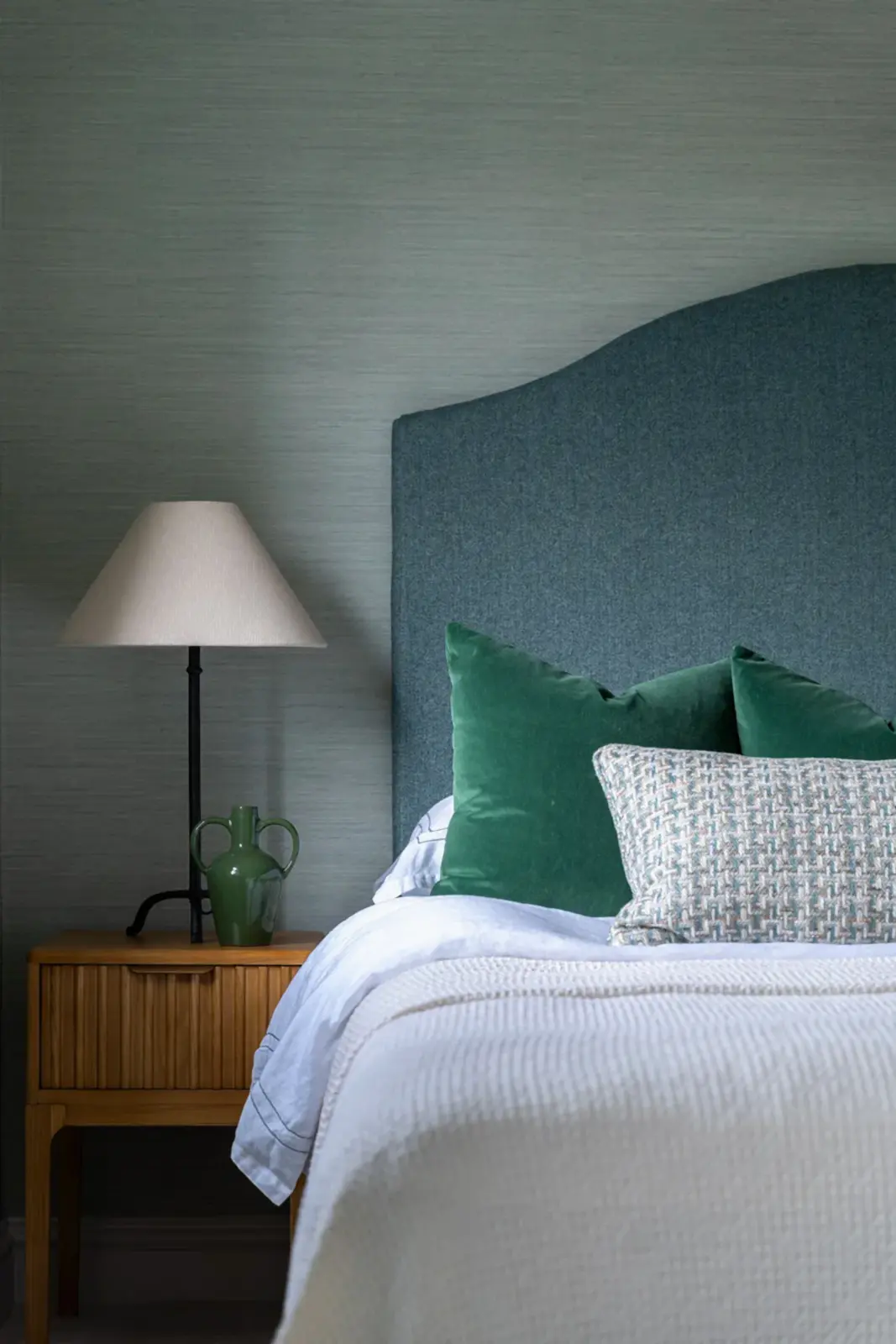 Show home bedroom with green upholstered headboard and textured wallpaper