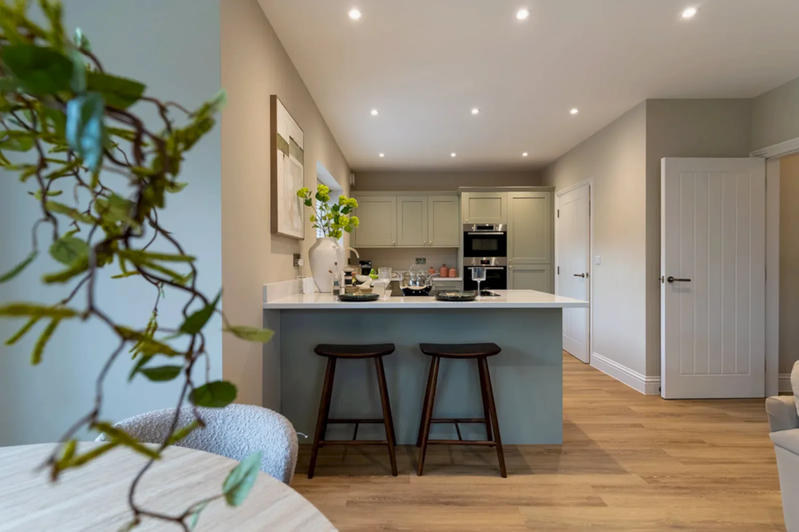 Show home kitchen with sage island and bar stools, styled by WildKind Interiors